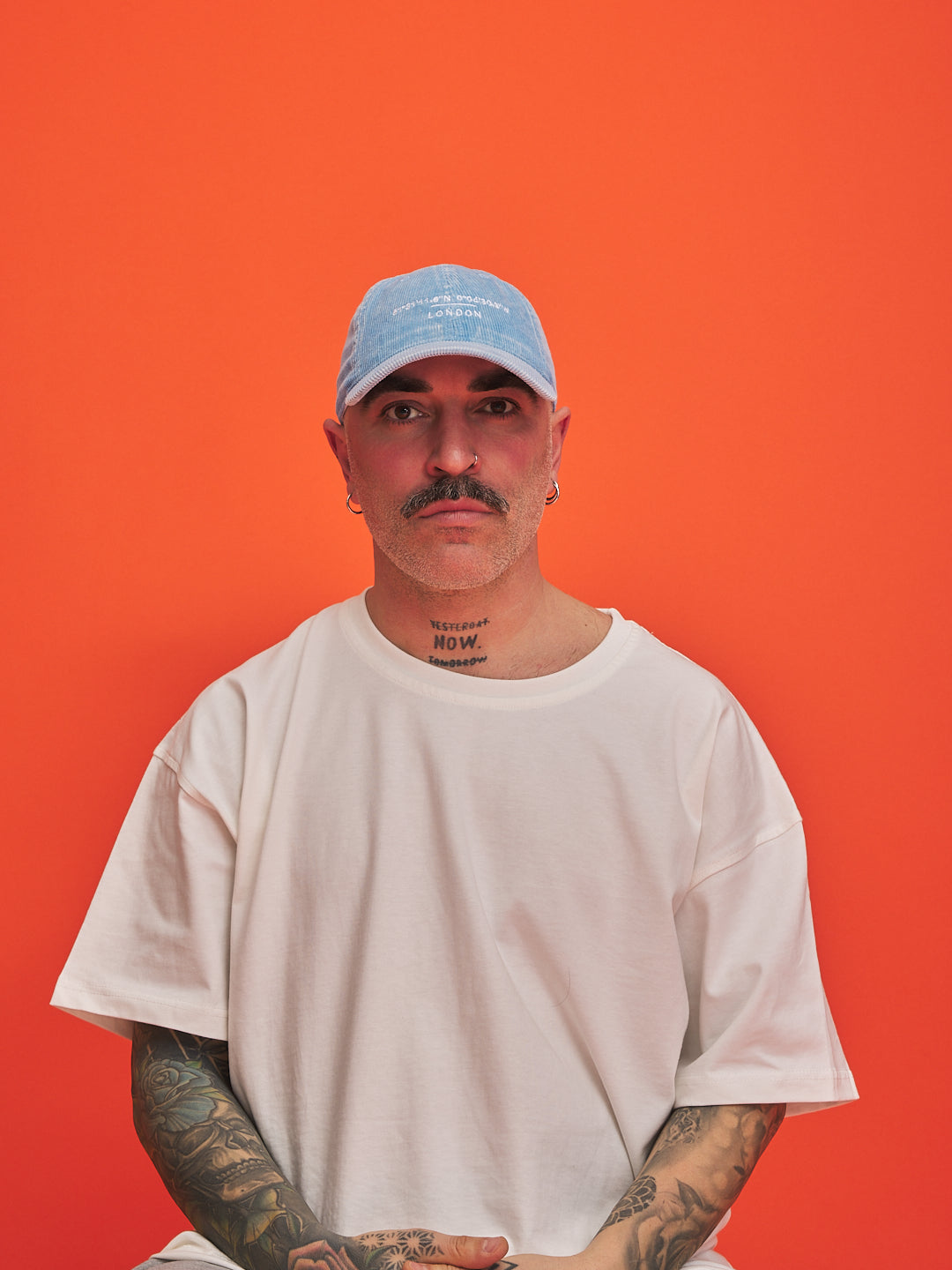 Man wearing a light blue cap and white t-shirt against an orange background