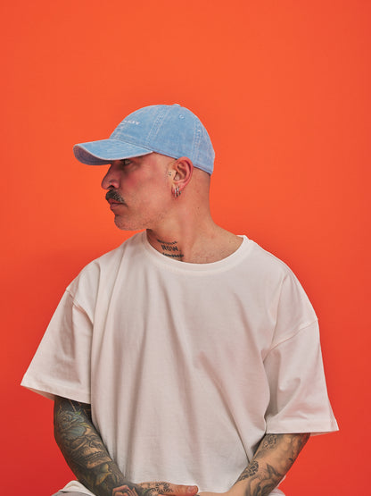 Person wearing a blue cap and white t-shirt against an orange background