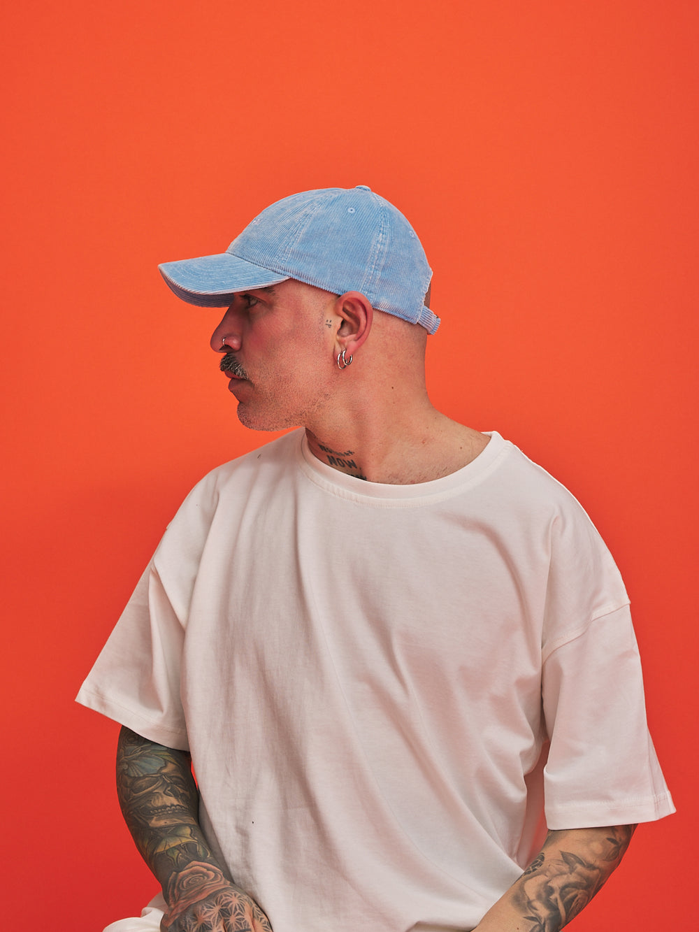 Person wearing a light blue cap and white t-shirt against an orange background