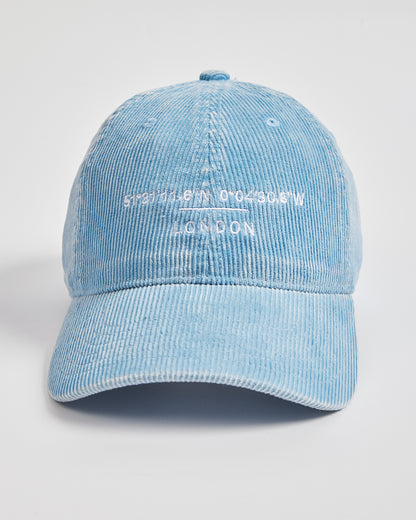 Light blue corduroy cap with white text on a light gray background