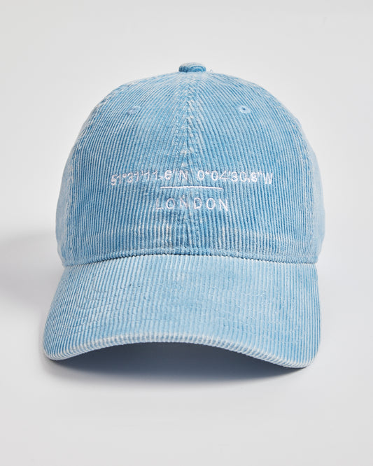 Light blue corduroy cap with white text on a light gray background