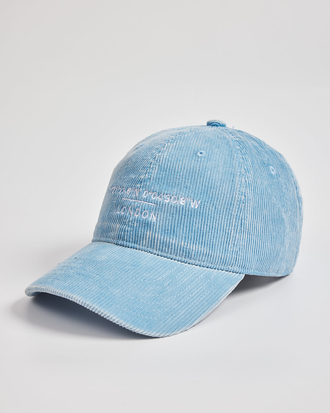 Light blue denim cap with branding on a light gray background