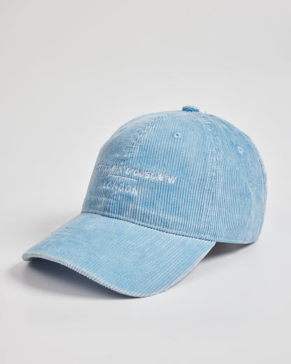 Light blue denim cap with branding on a light gray background
