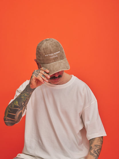 Person wearing a cap and white t-shirt against an orange background