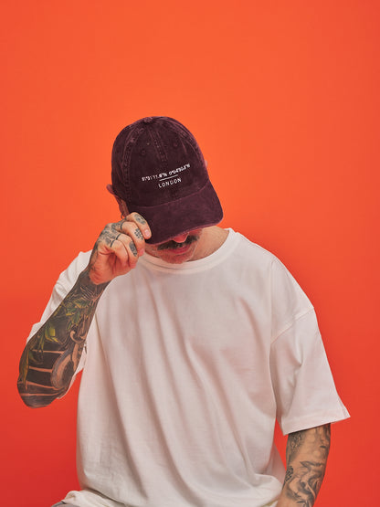 Person wearing a maroon cap with text on an orange background