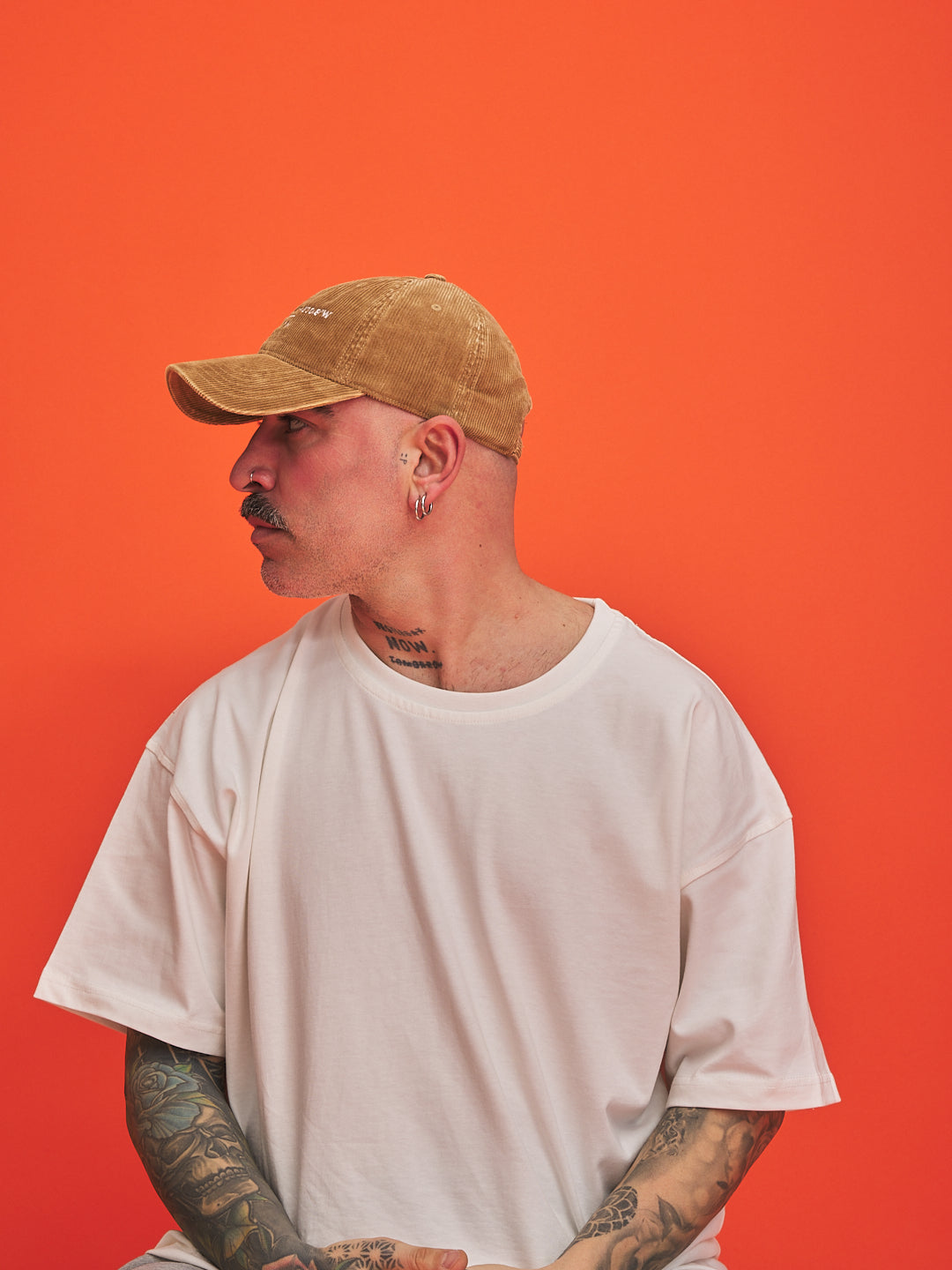 Man wearing a camel cap and white t-shirt against an orange background