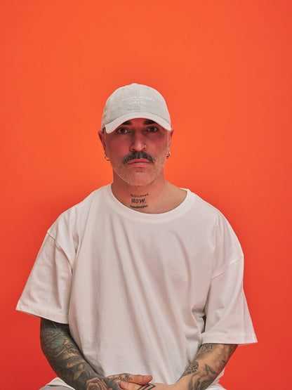 Man wearing a white cap and t-shirt against an orange background