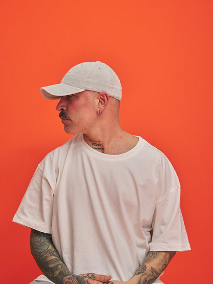 Person wearing a white cap and t-shirt against an orange background