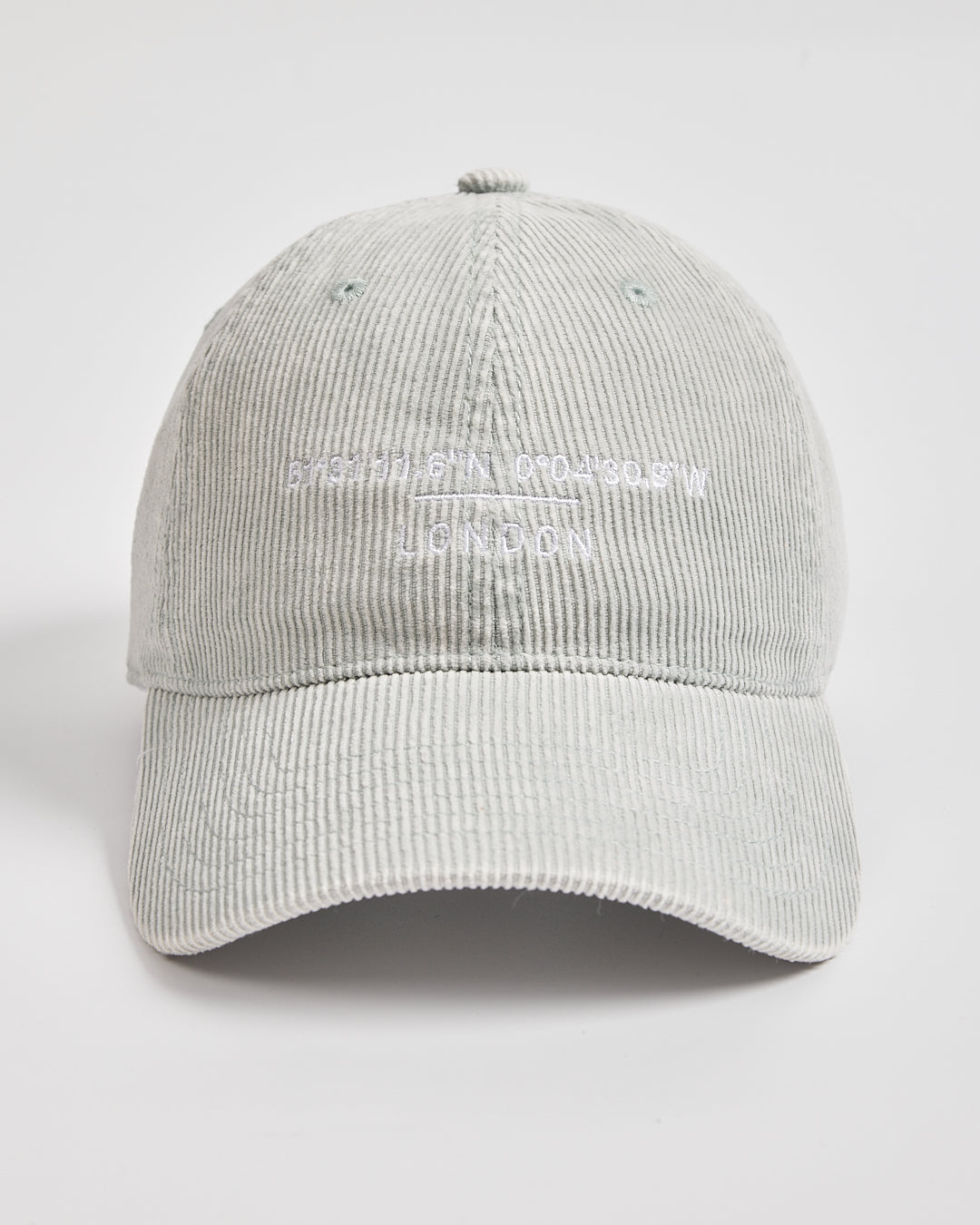Light gray corduroy cap with white text on a light gray background