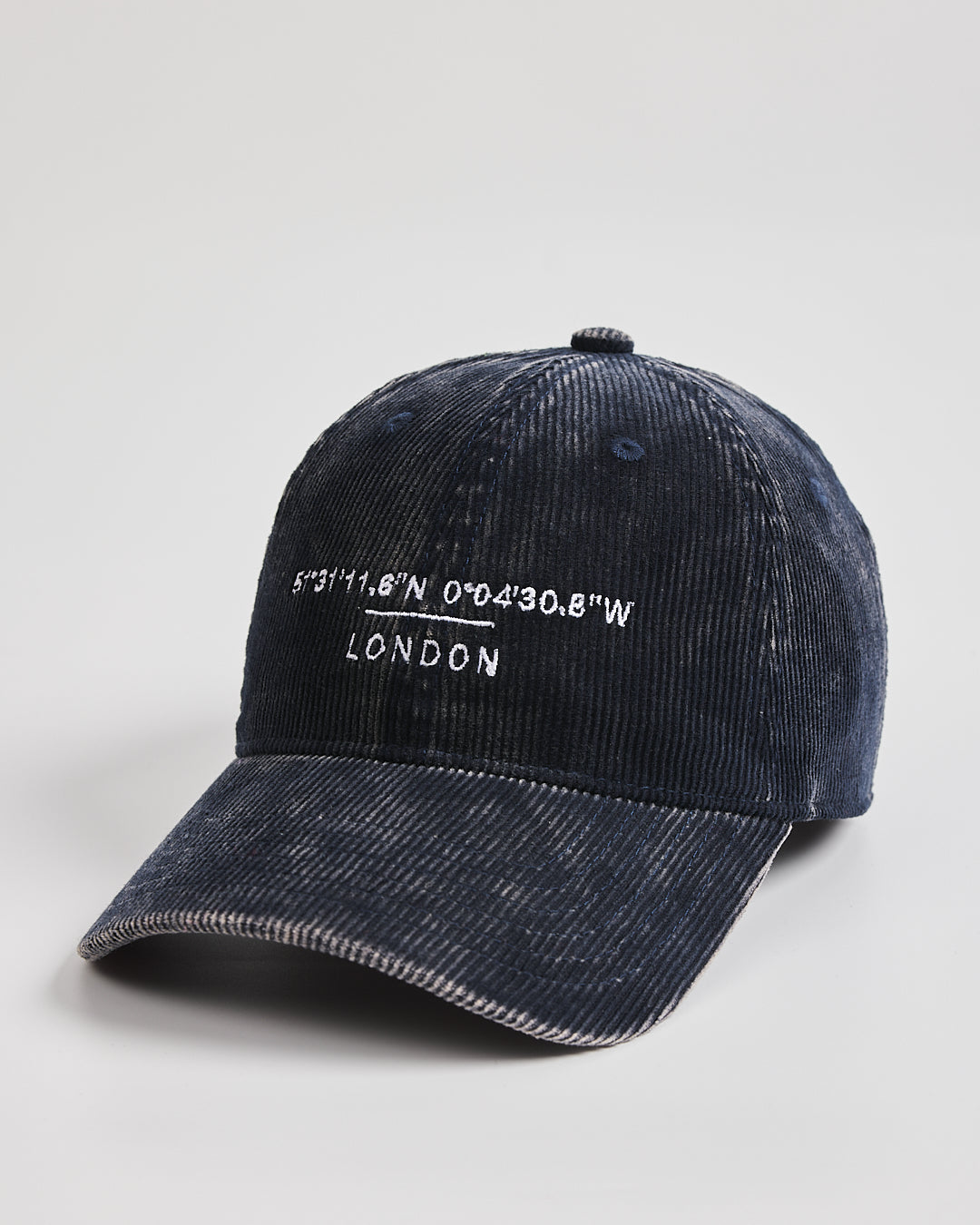 Navy cap with 'London' and coordinates on a light gray background