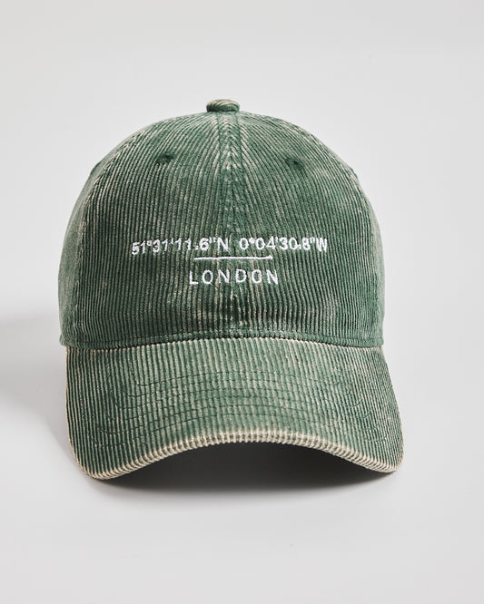 Green corduroy cap with embroidered text on a light gray background