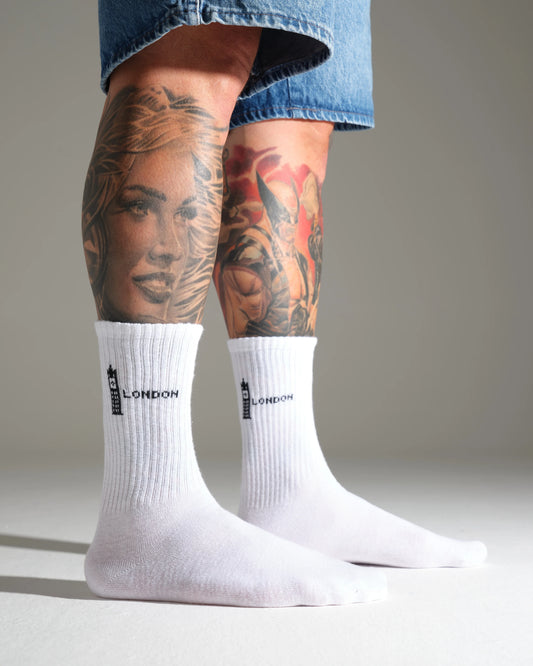 White socks with ' London Big Ben' branding worn by a person with tattoos on a neutral background