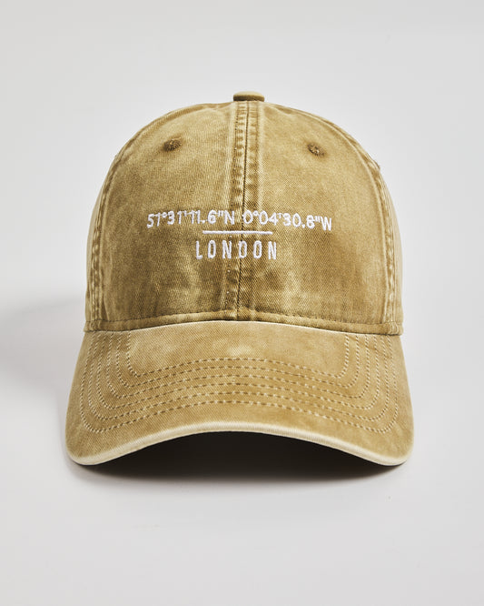 Yellow cap with 'London' and coordinates printed on a light gray background