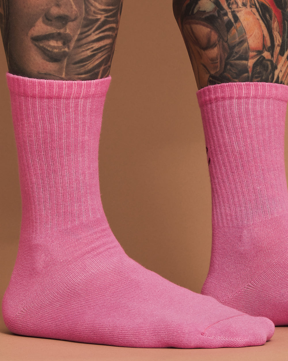 Pink socks worn with tattoos on a brown background