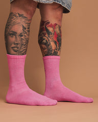 Person wearing pink socks with tattoos on a brown background