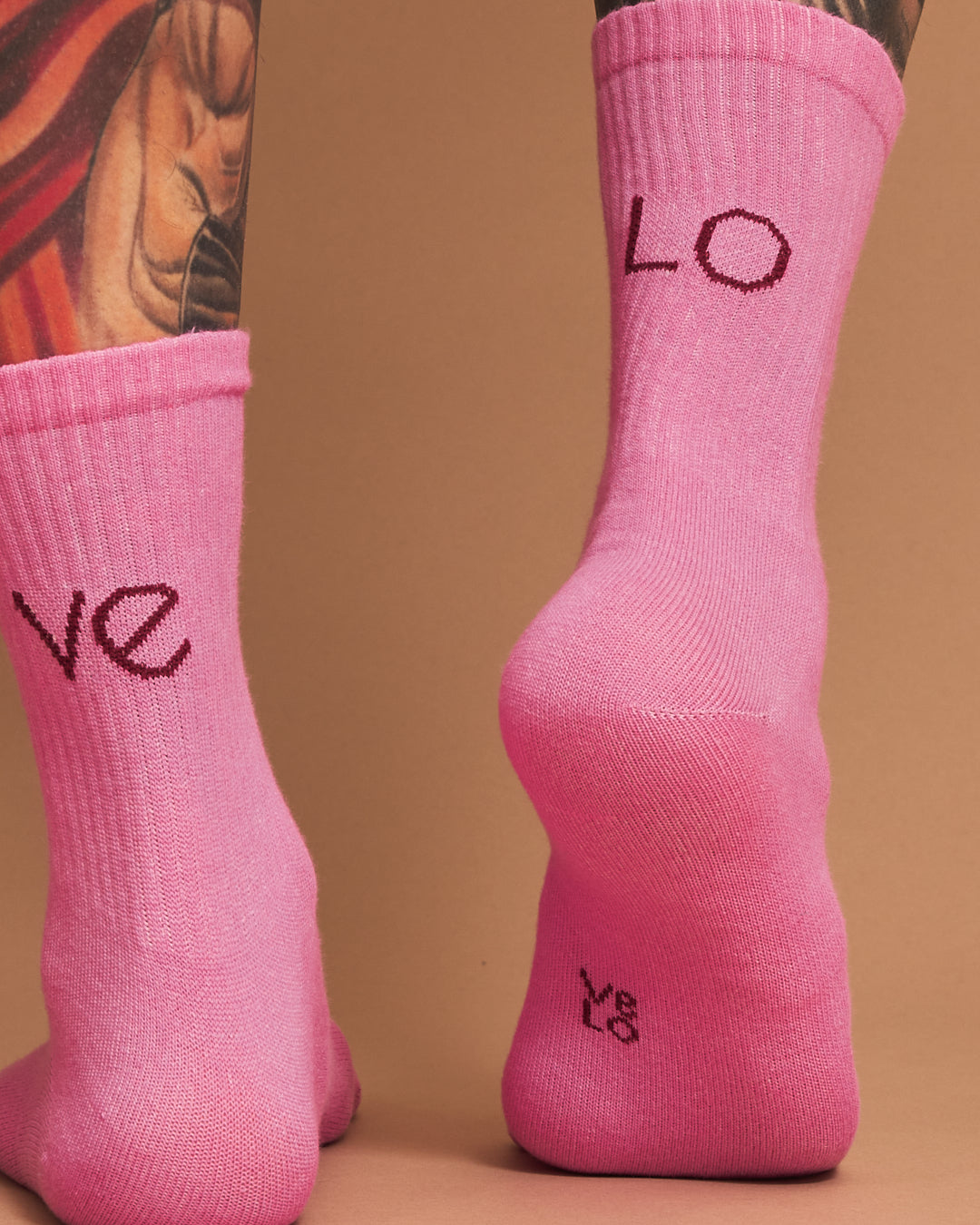 Pink socks with 'LOVE' text worn by a person on a brown background