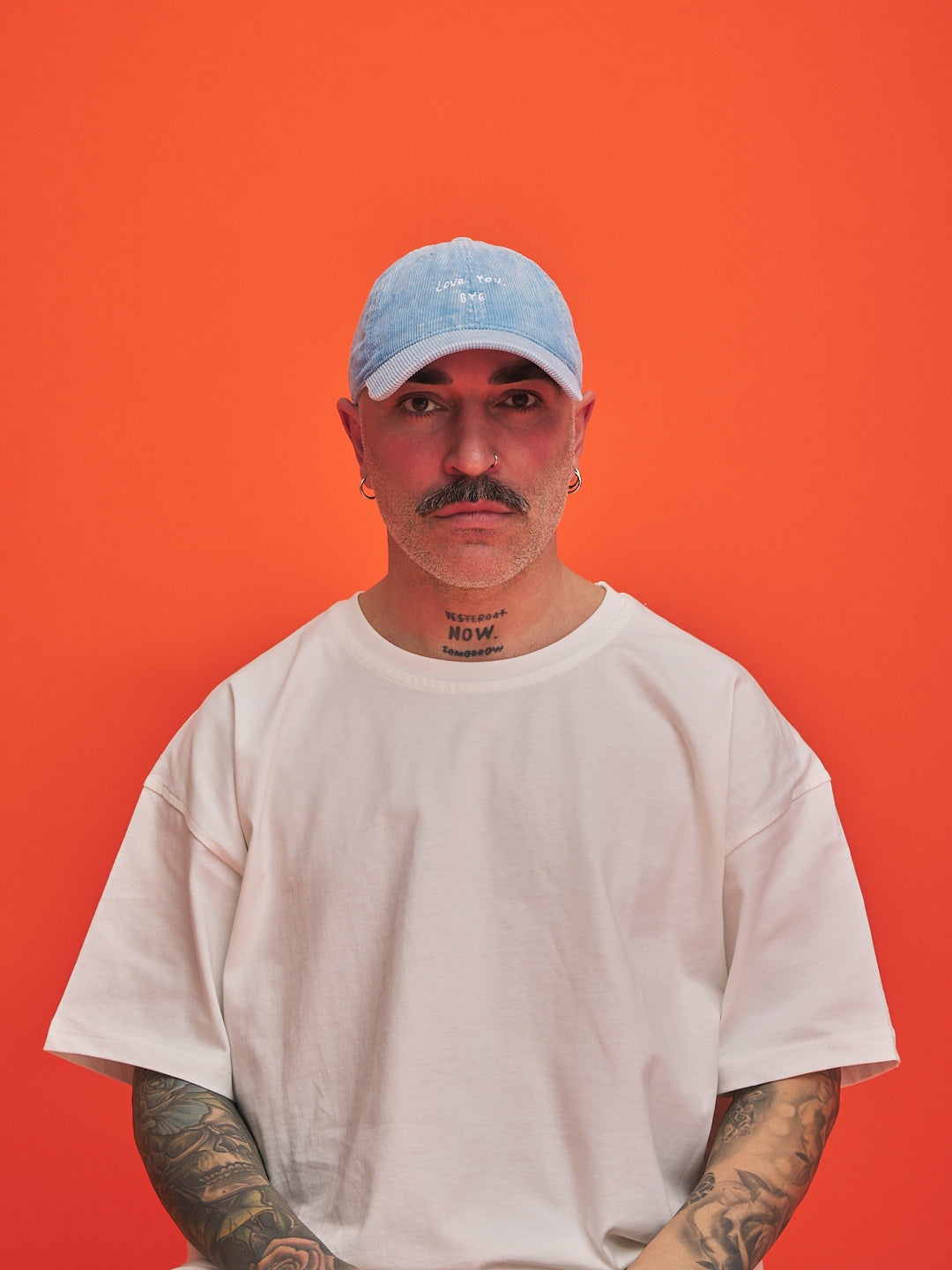 Man wearing a light blue cap and white t-shirt against an orange background