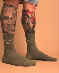Person wearing green socks with text, standing against an orange background