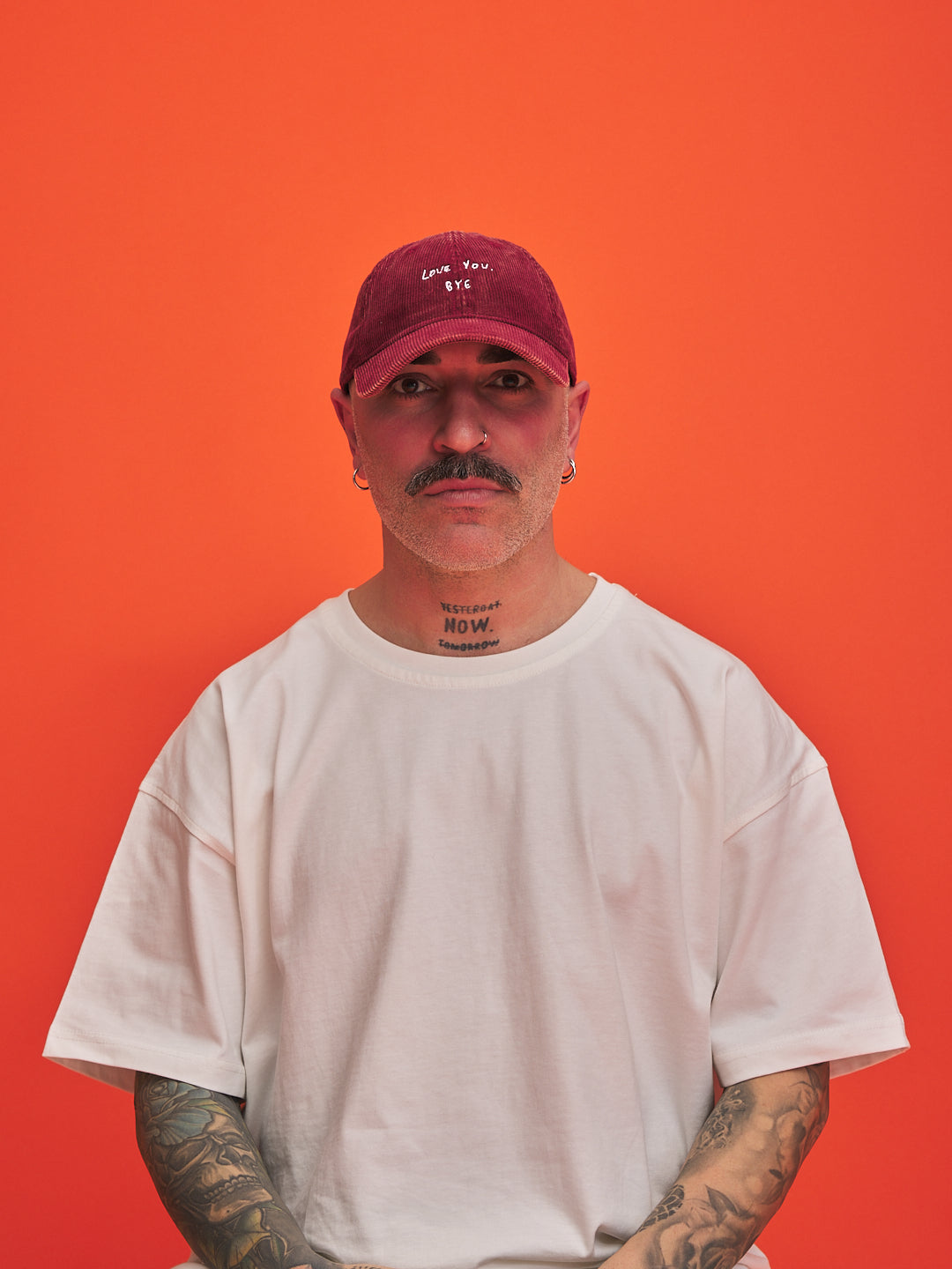 Man wearing a red cap and white t-shirt against an orange background