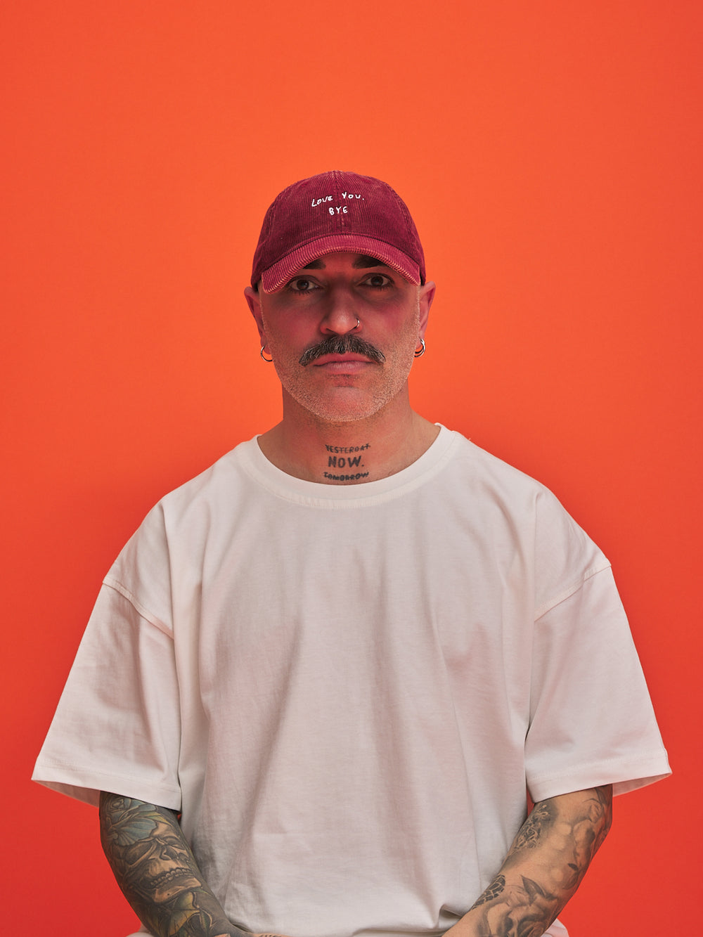 Man wearing a red cap and white t-shirt against an orange background