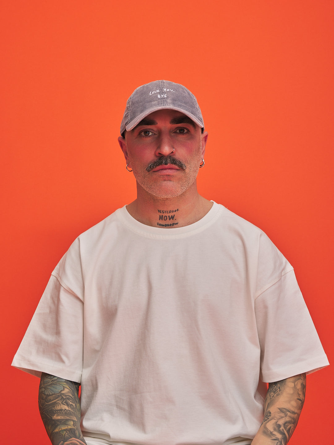 Man wearing a gray cap and white t-shirt against an orange background