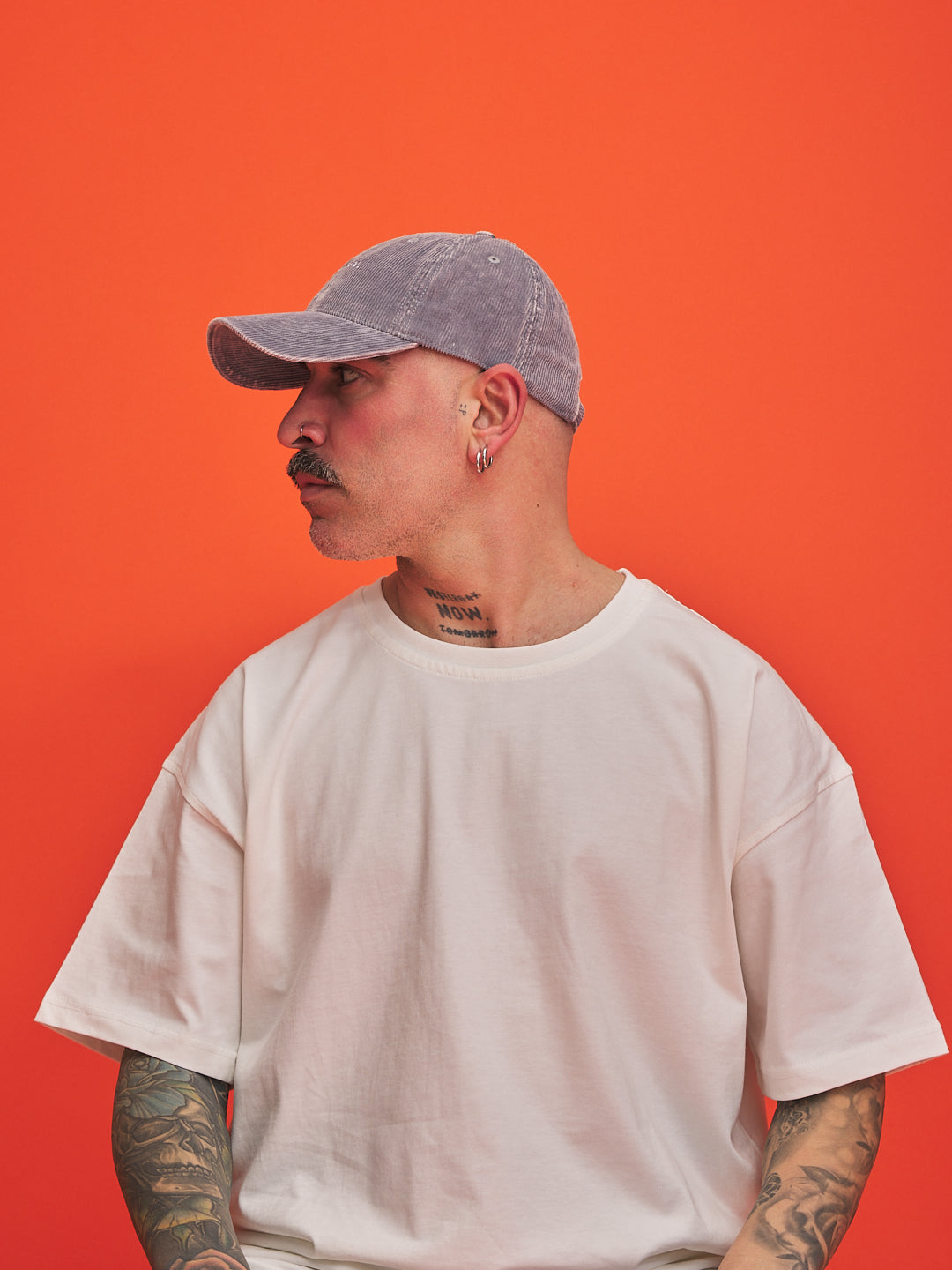 Person wearing a gray cap and white t-shirt against an orange background