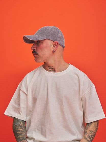 Person wearing a gray cap and white t-shirt against an orange background