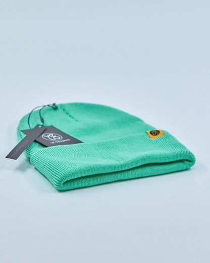 Green beanie with a tag on a light blue background