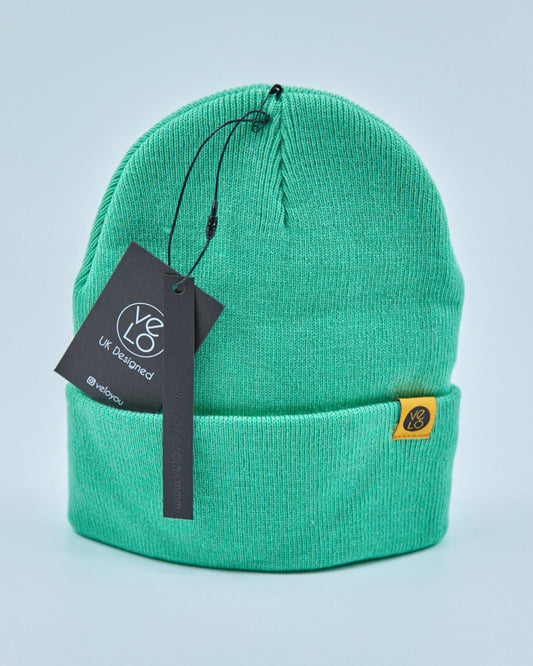 Mint green beanie with a tag on a light blue background