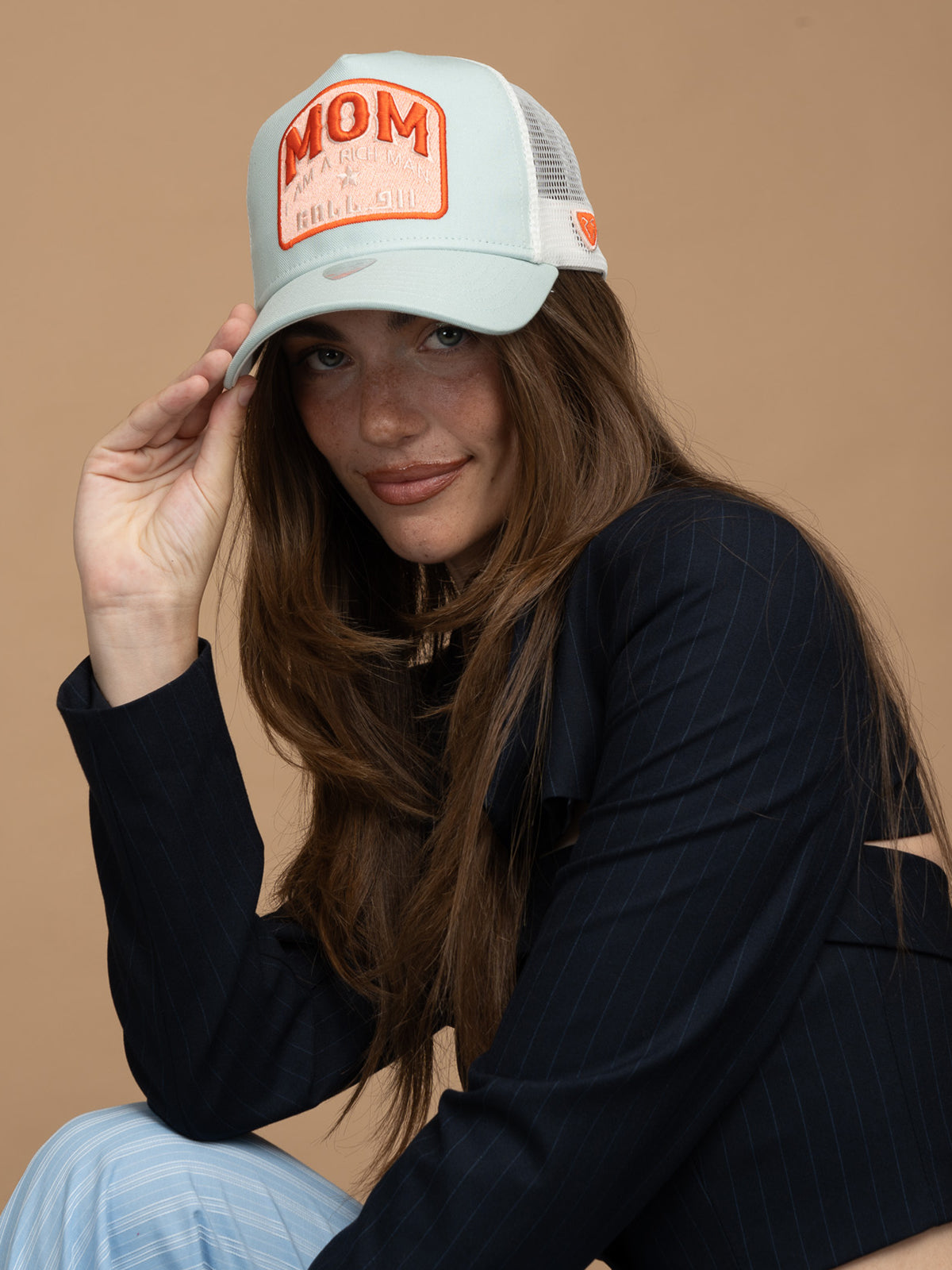 Woman wearing Mom Mint Green Trucker Hat on a beige background