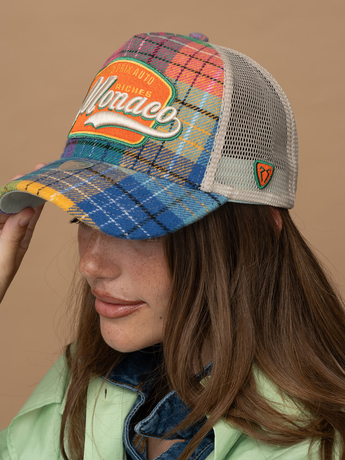 Person wearing Monaco Green Trucker Hat on a beige background