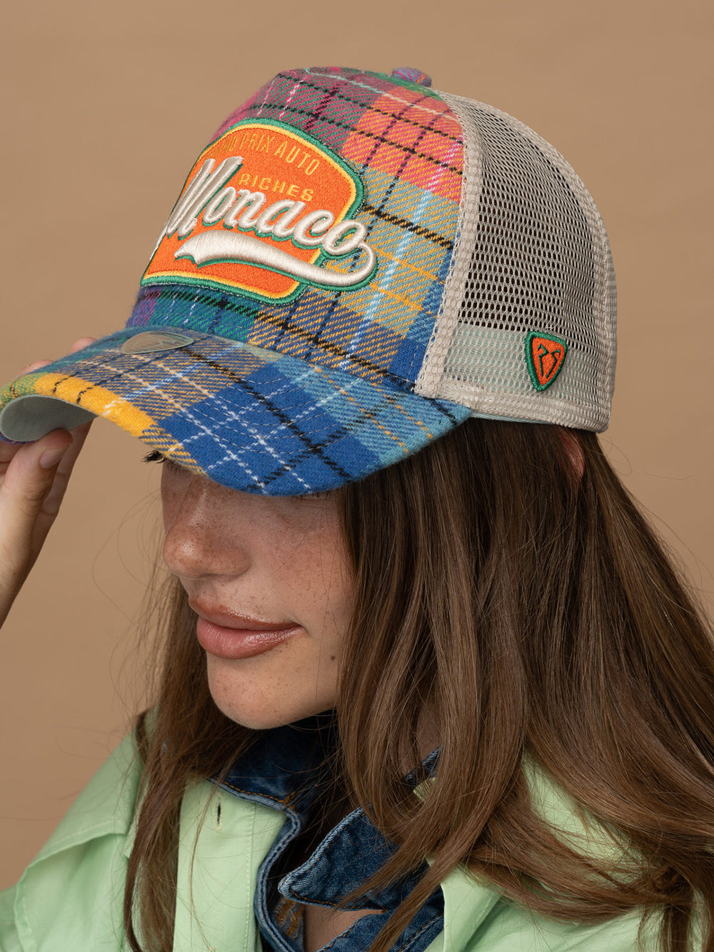 Person wearing Monaco Green Trucker Hat on a beige background