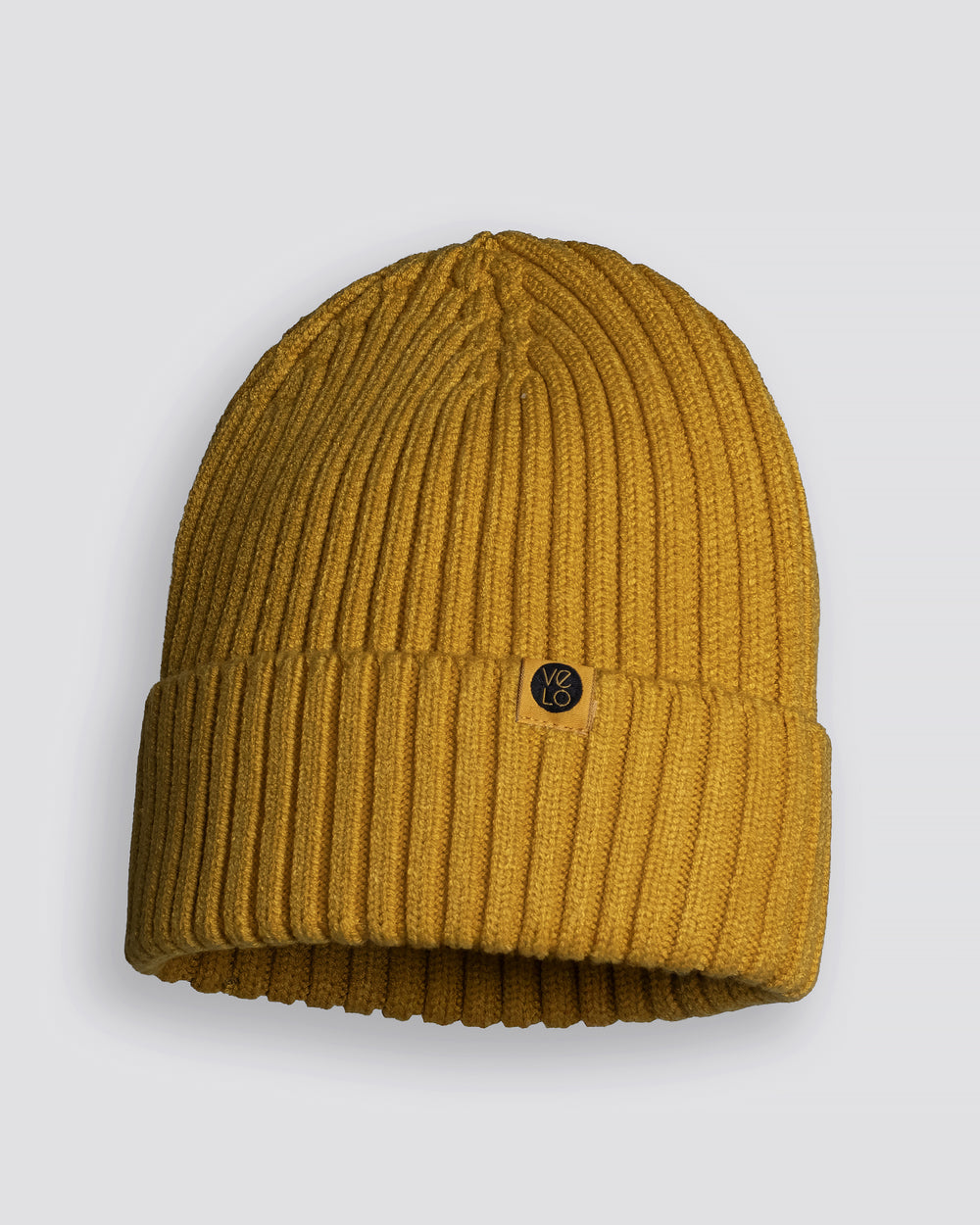 Mustard yellow beanie with a brand logo on a light gray background