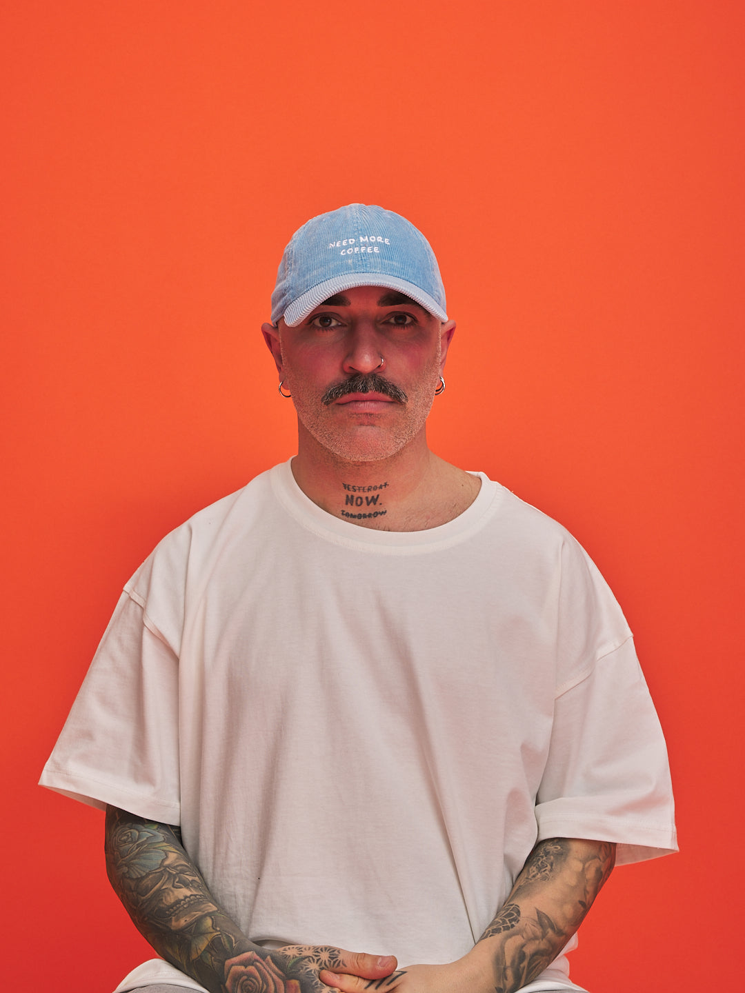 Man wearing a light blue cap and white t-shirt against an orange background