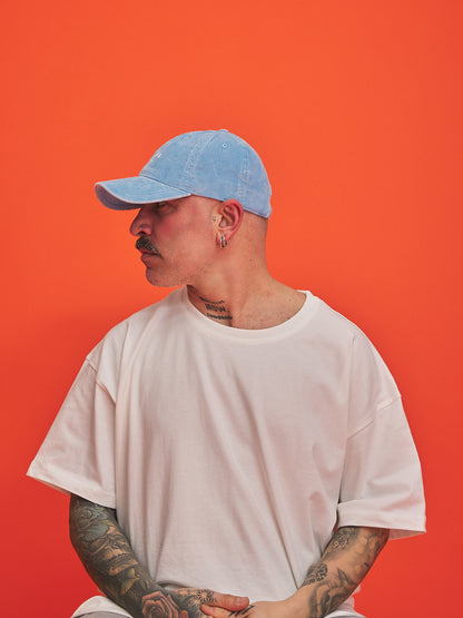 Person wearing a light blue cap and white t-shirt against an orange background