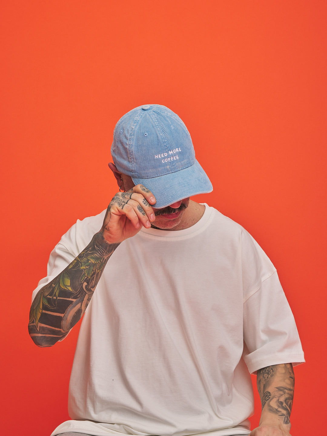 Person wearing a blue cap and white t-shirt against an orange background