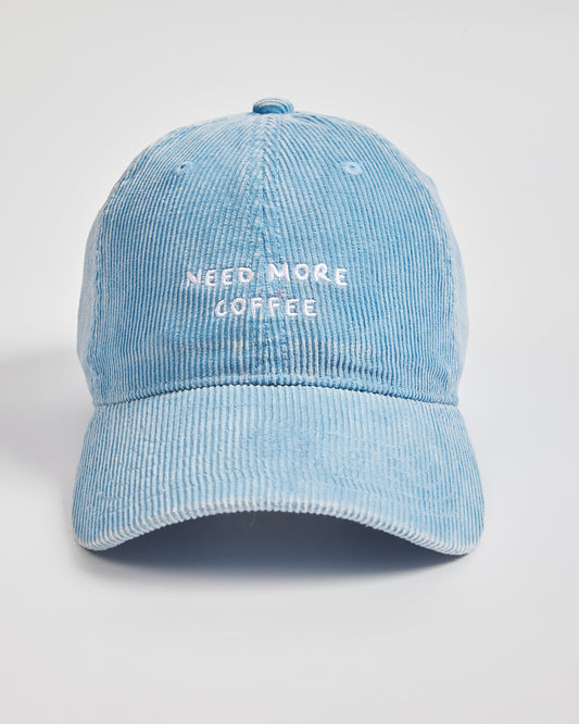 Light blue denim cap with 'Need More Coffee' text on a light gray background
