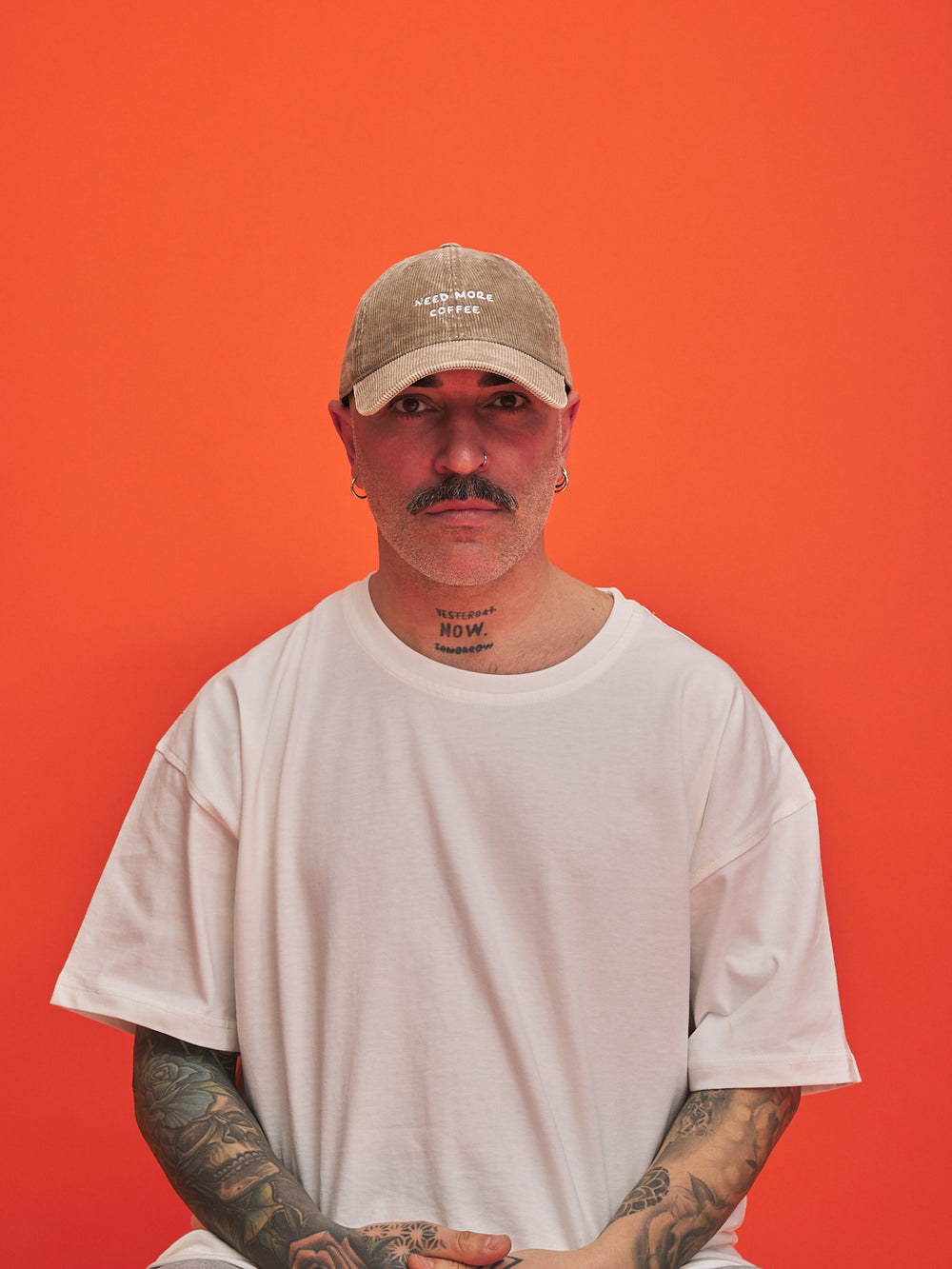 Man wearing a beige cap and white t-shirt against an orange background