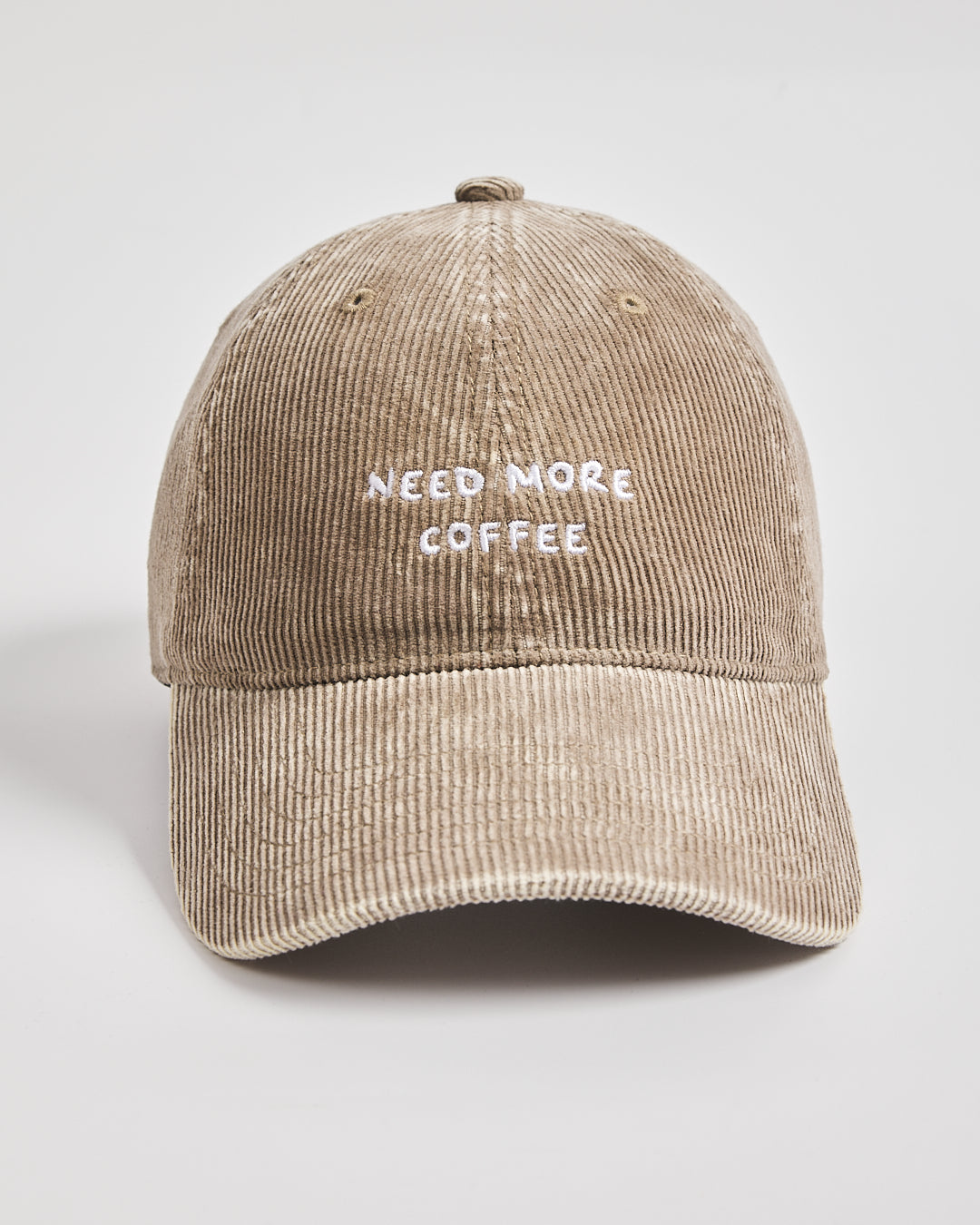 Beige cap with 'Need More Coffee' text on a light gray background