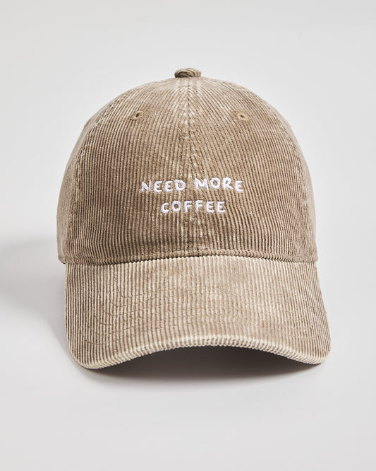 Beige cap with 'Need More Coffee' text on a light gray background