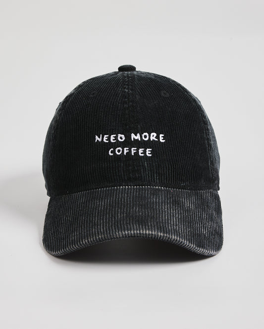 Black cap with 'NEED MORE COFFEE' text on a light gray background