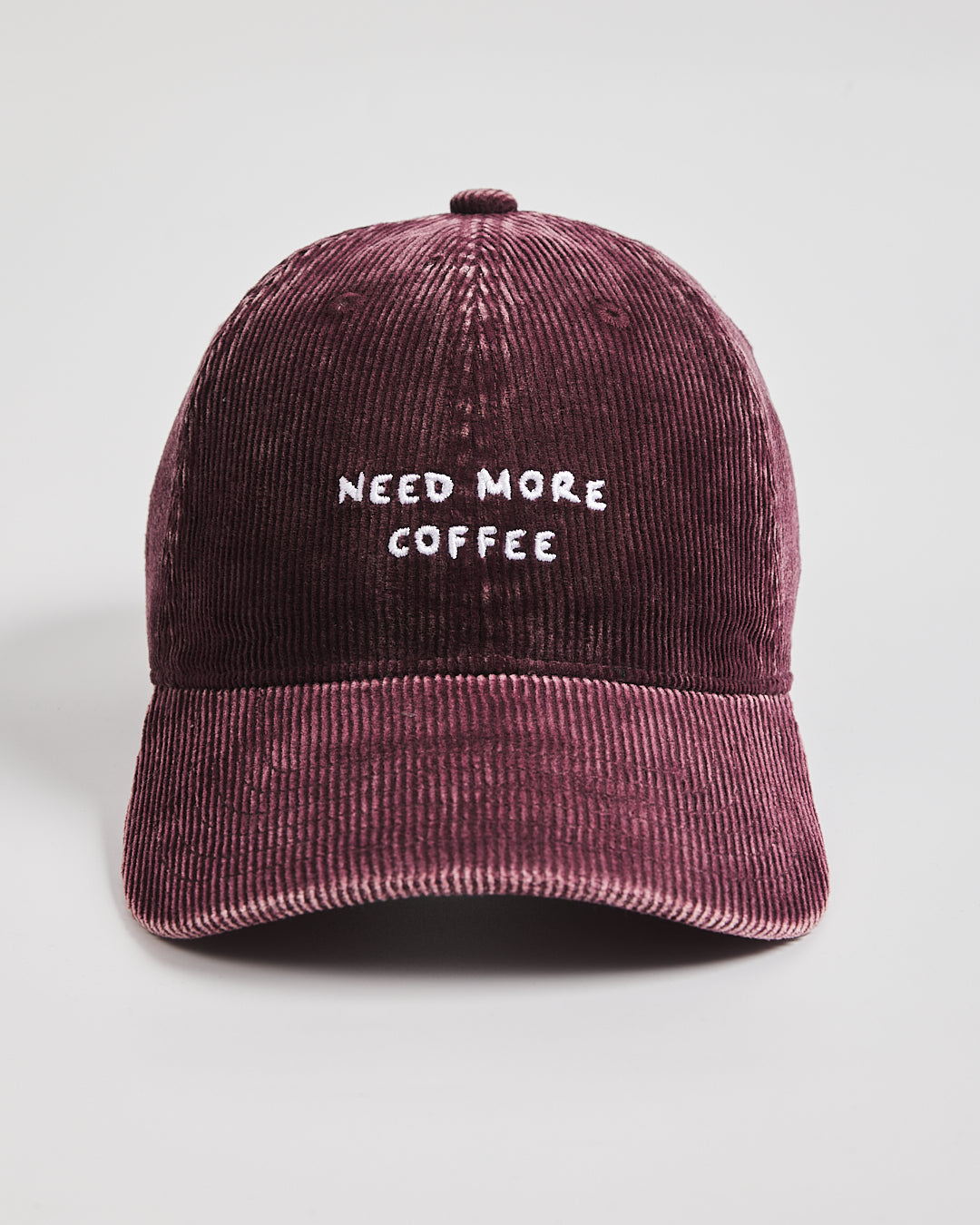 Maroon corduroy cap with 'NEED MORE COFFEE' text on a light gray background