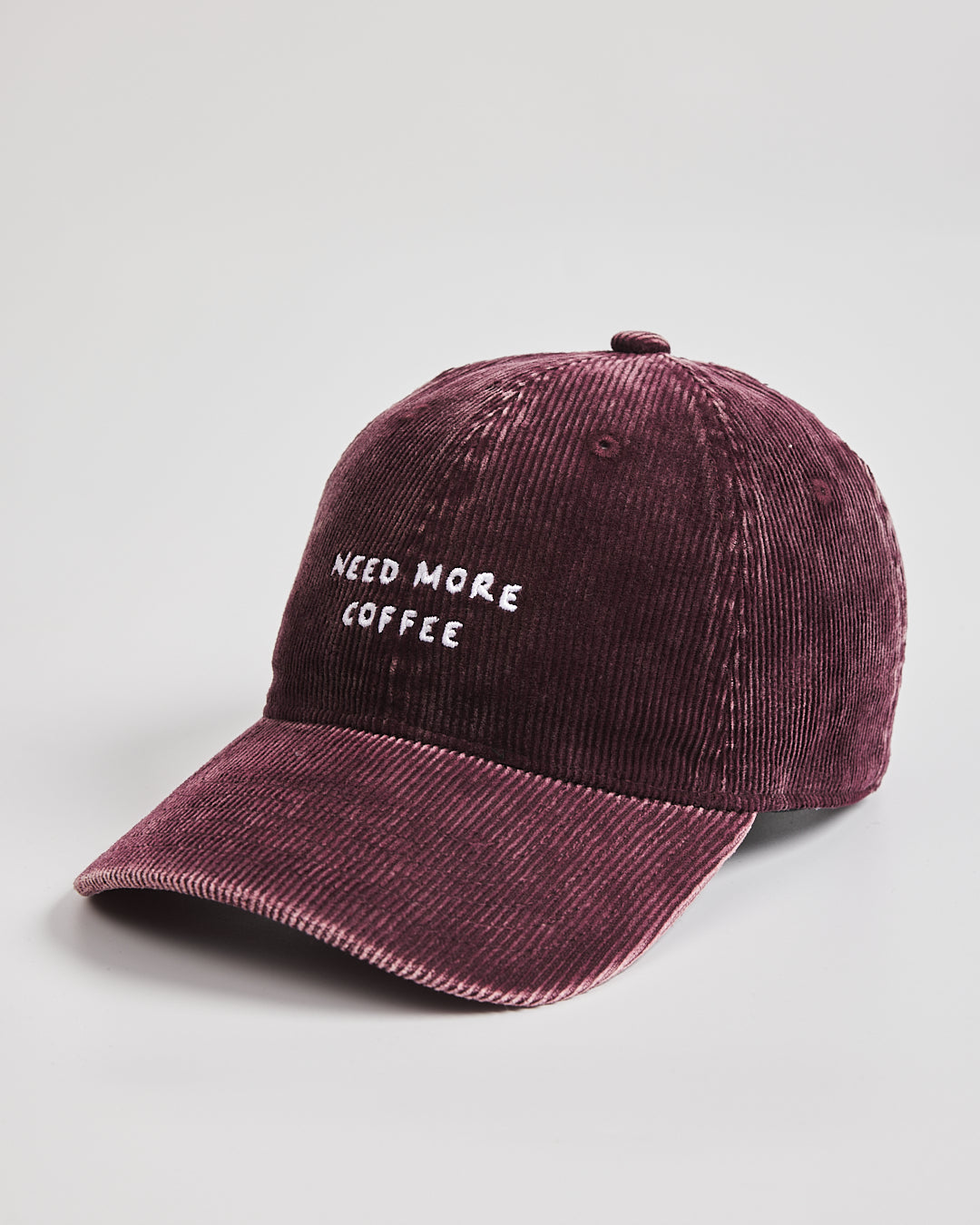 Maroon cap with 'Need More Coffee' text on a light gray background