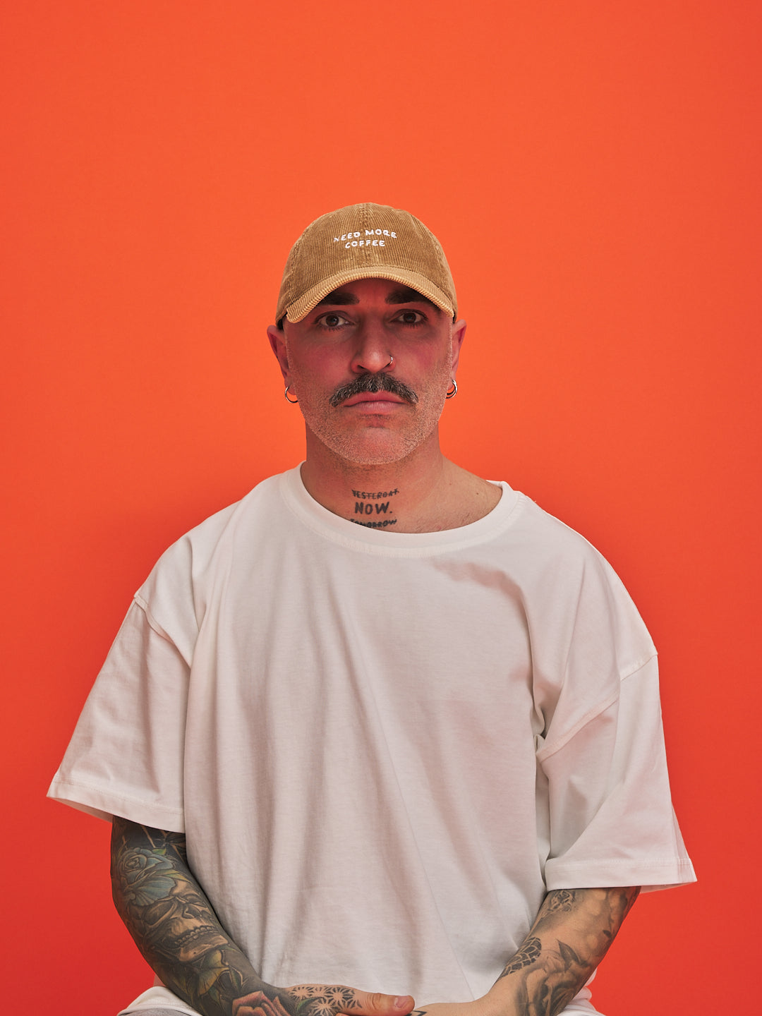 Man wearing a camel cap and white t-shirt against an orange background