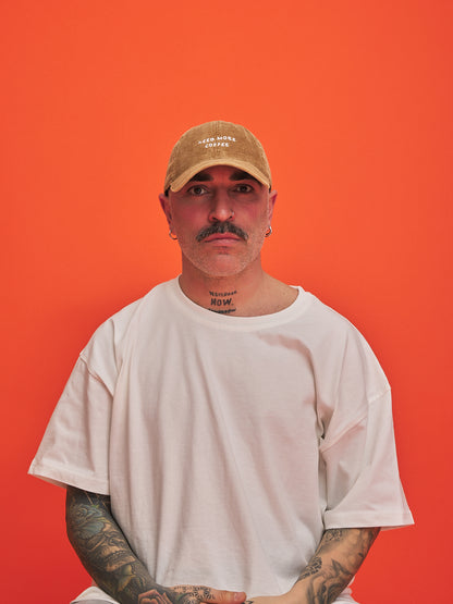Man wearing a camel cap and white t-shirt against an orange background