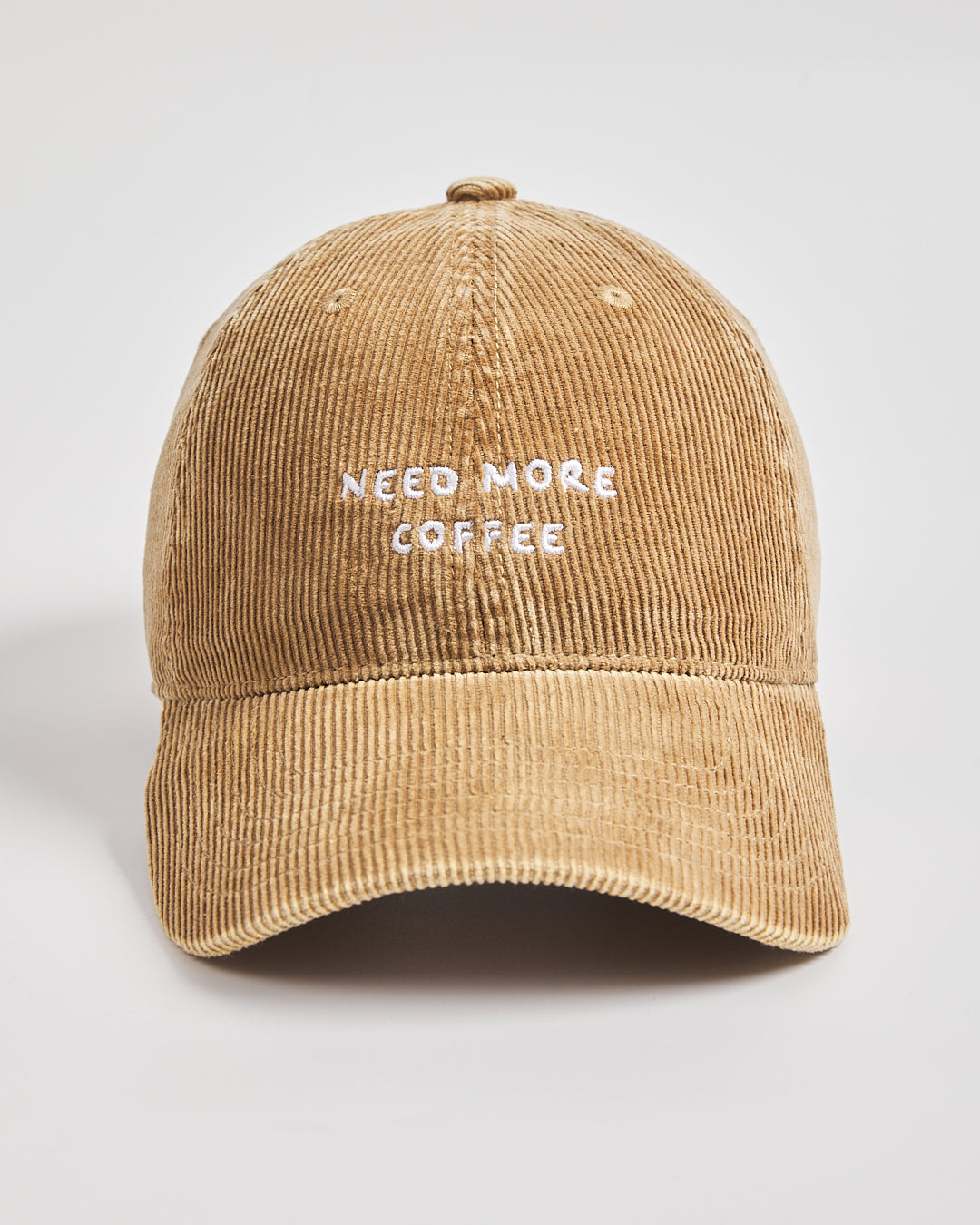Camel corduroy cap with 'Need More Coffee' text on a light gray background