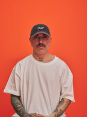 Man wearing a cap and white t-shirt against an orange background