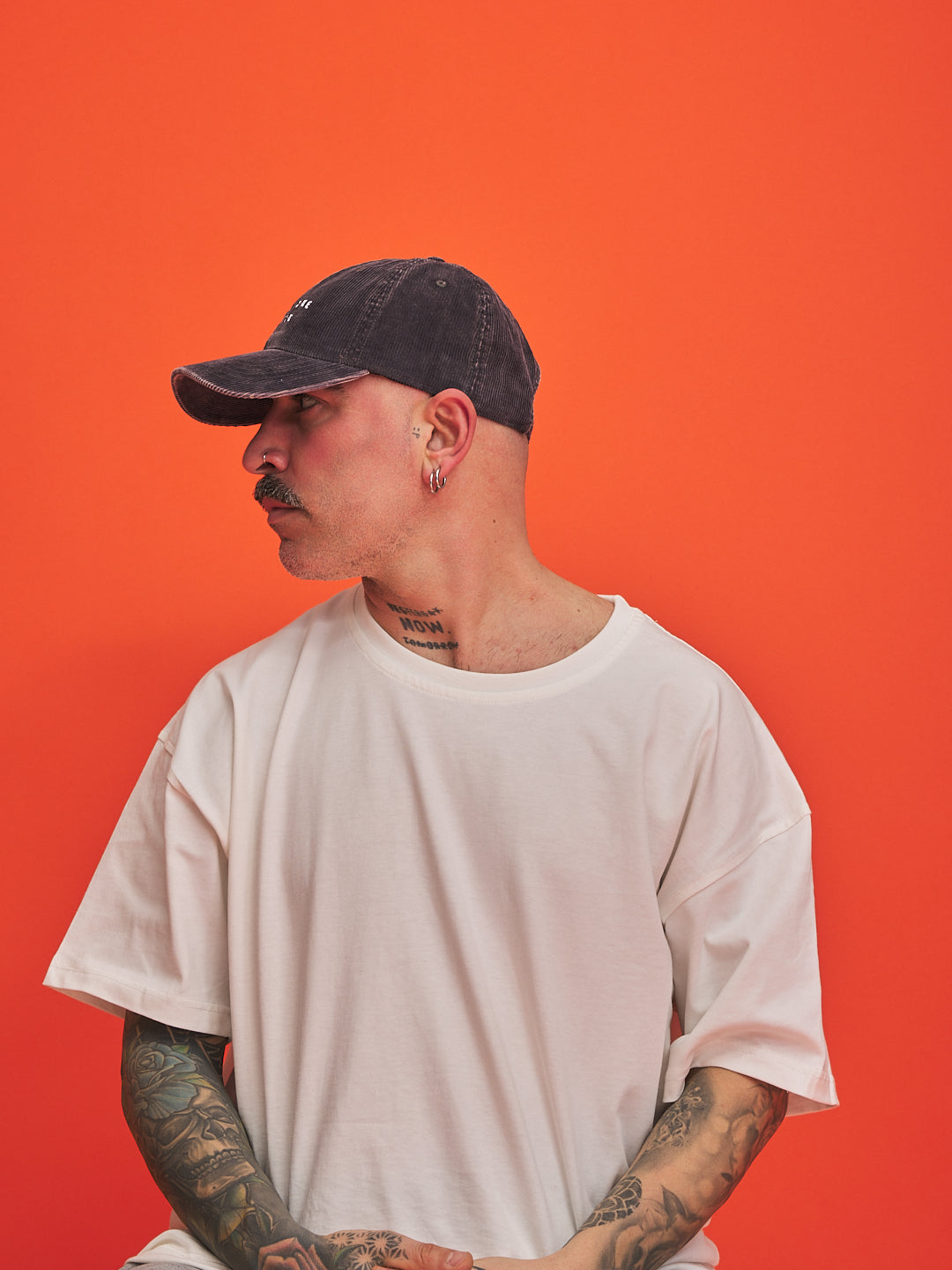 Man wearing a cap and white t-shirt against an orange background