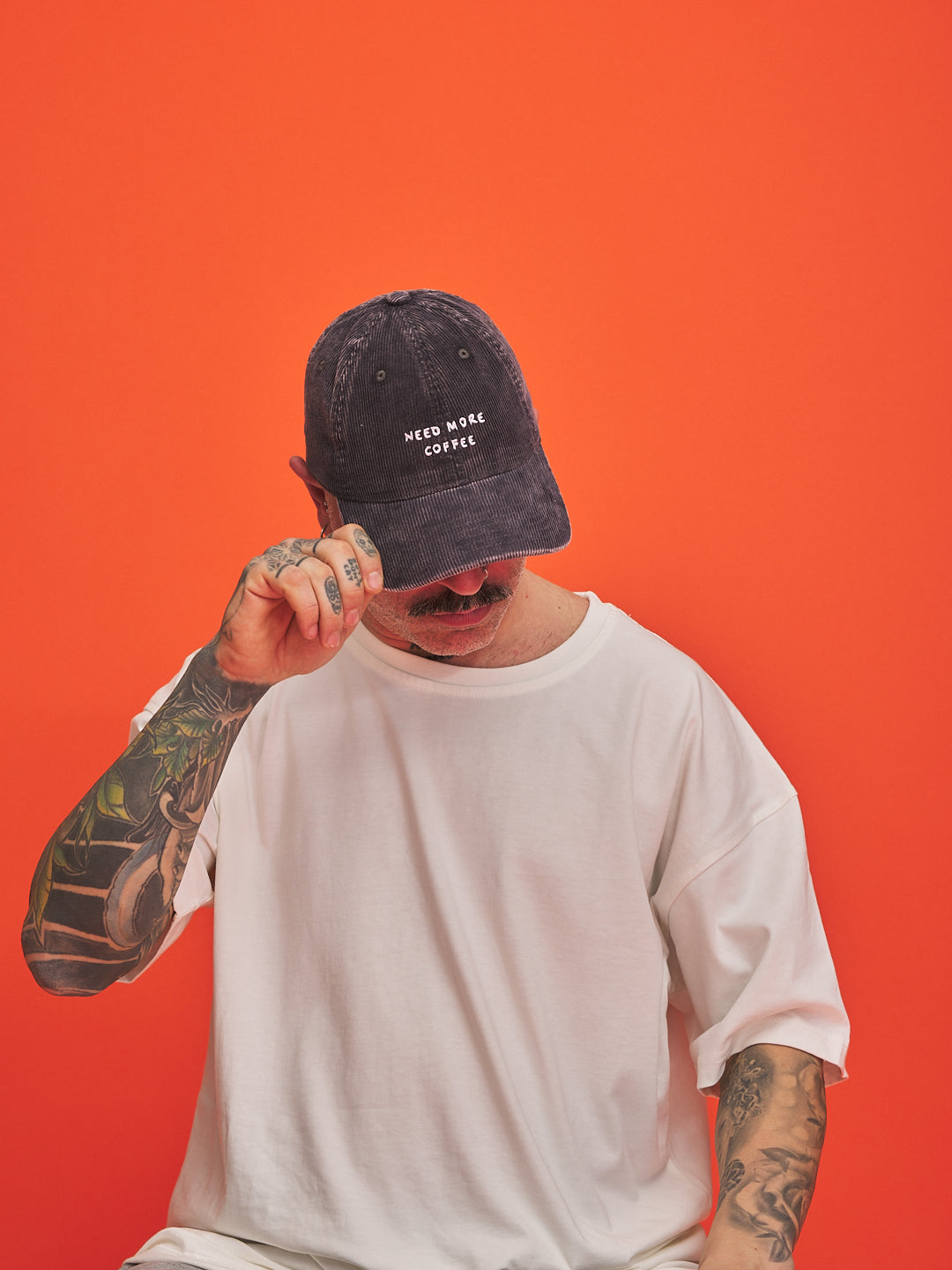Person wearing a black cap and white t-shirt against an orange background