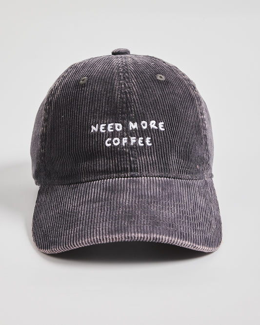 Black corduroy cap with 'Need More Coffee' text on a light gray background